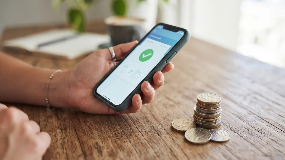 Smartphone showing an instant bank transfer confirmation with Australian dollar coins stacked nearby