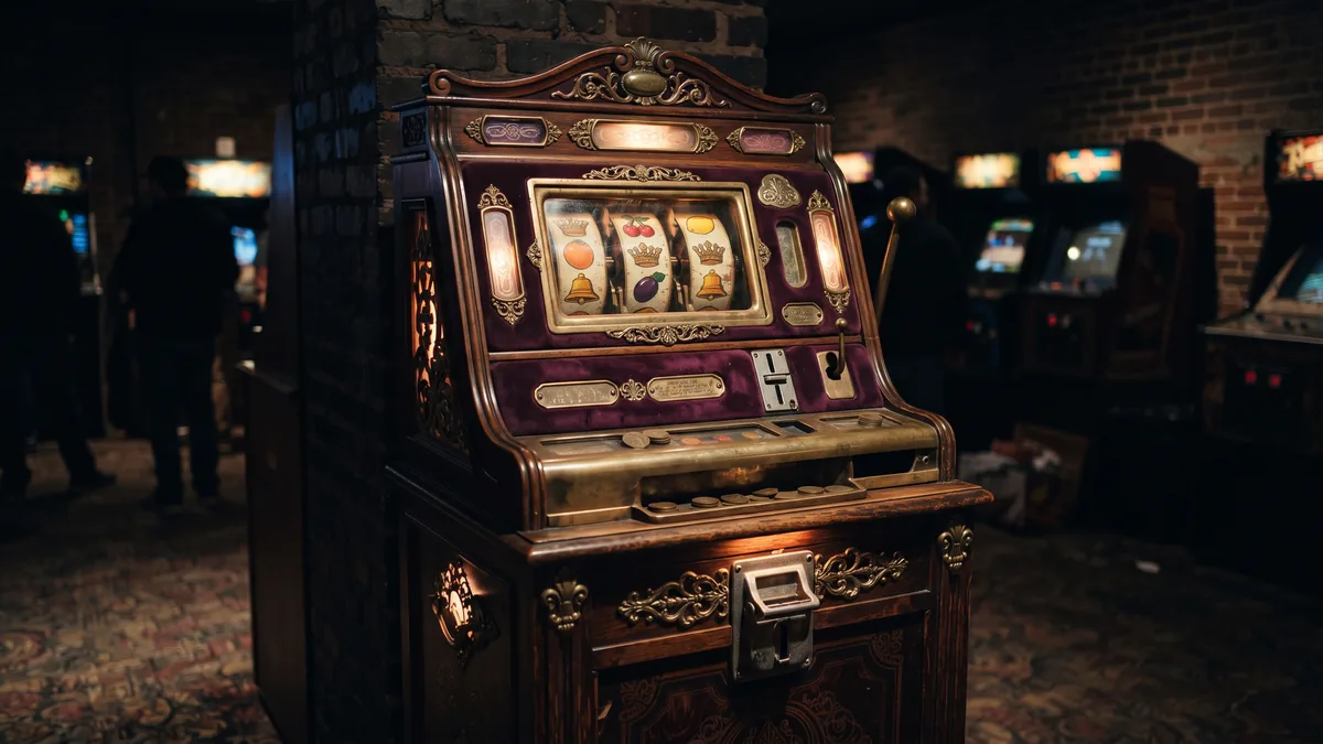 Vintage amusement cabinet with three mechanical reels showing crown and fruit symbols